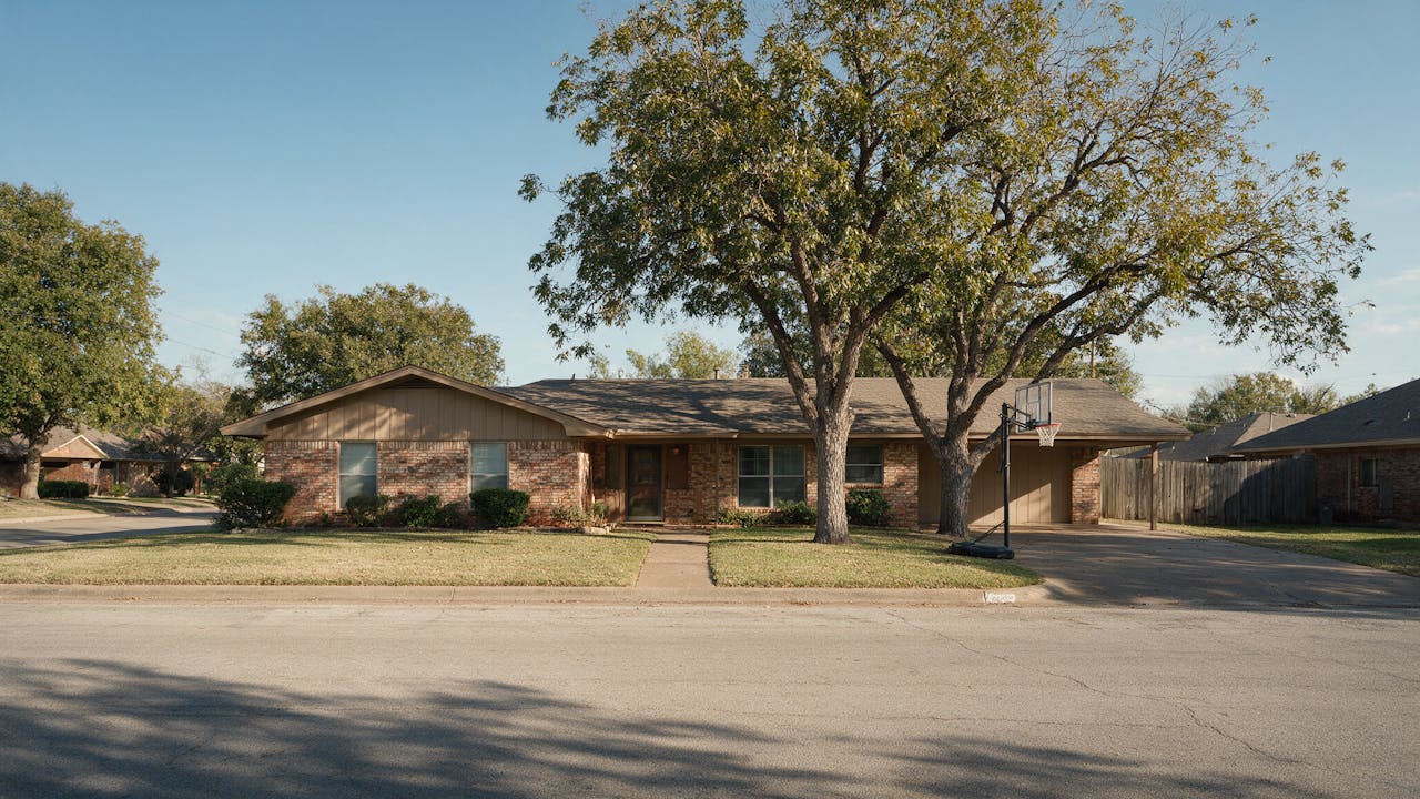 A brick ranch home on a wide residential street in Arlington, Texas