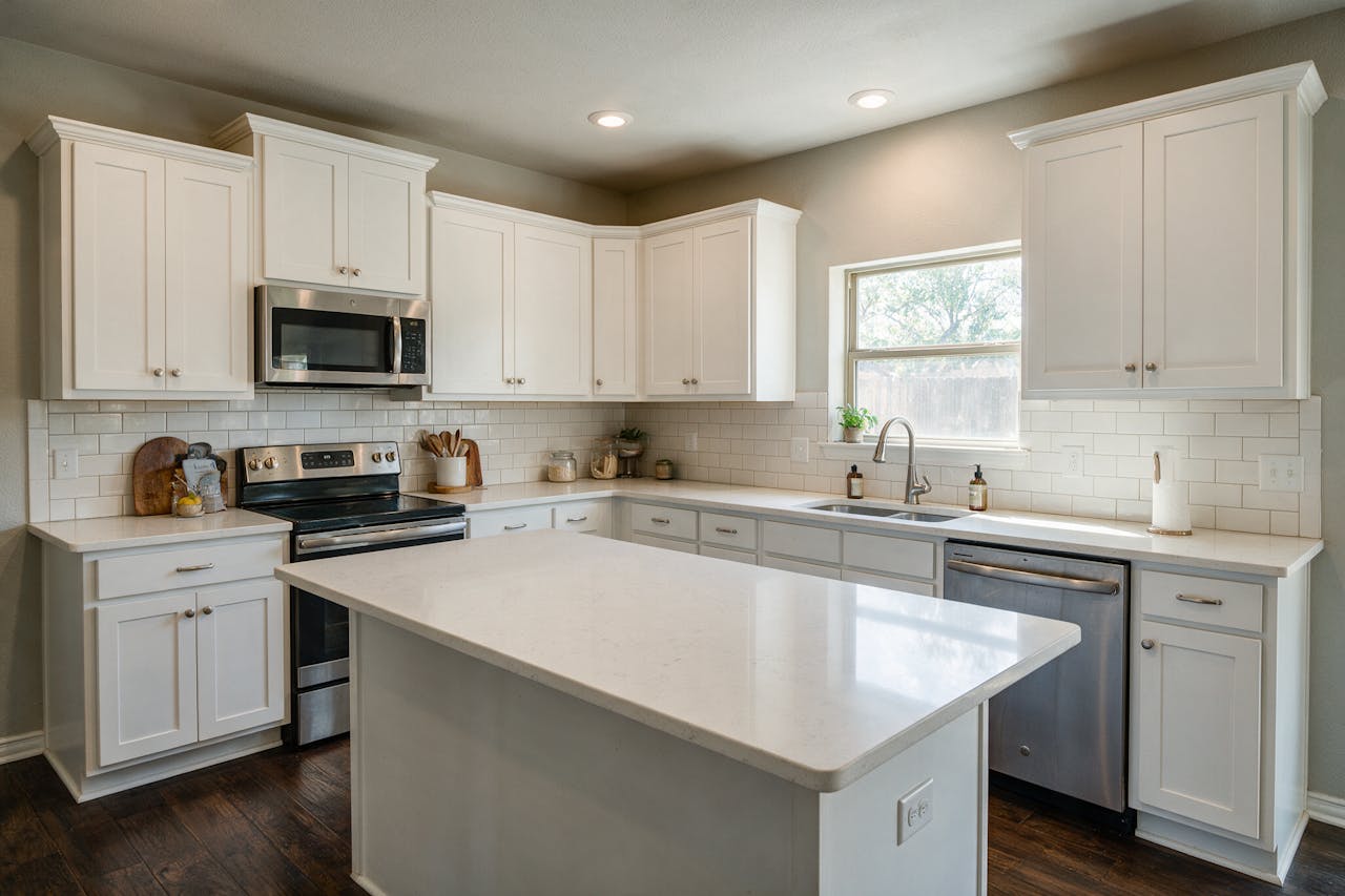 A finished kitchen remodel with white cabinets and a quartz island